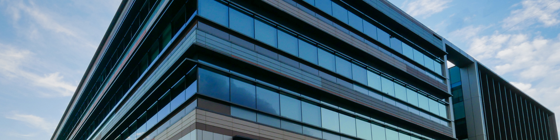 Modern glass office building corner with reflective blue windows