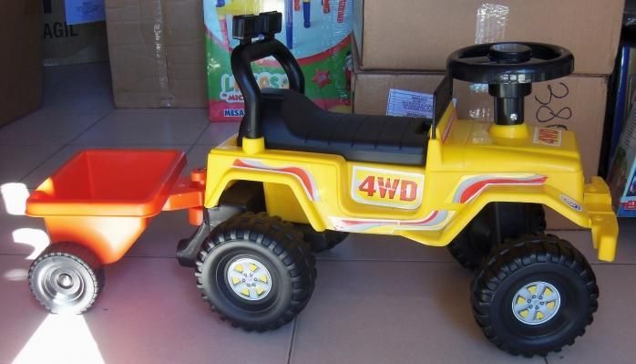 Jeep de juguete amarillo 4x4 remolcando un remolque rojo en un estante.
