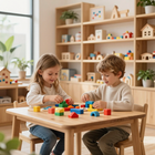Dos niños construyen con bloques de colores en una mesa de madera en una luminosa sala de juegos.