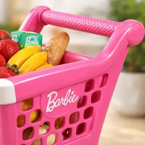 Cesta de la compra de juguete rosa de Barbie con fruta, pan y una caja de cartón verde en su interior.