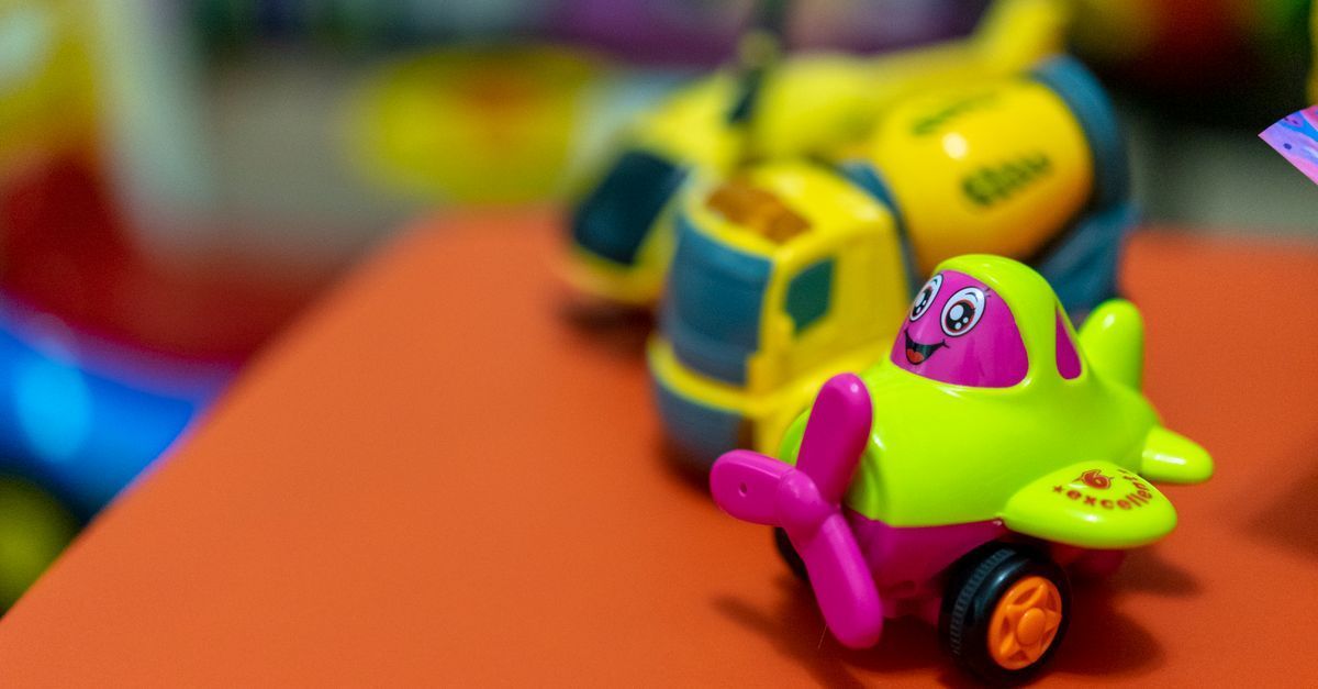 Coches de juguete coloridos sobre una superficie naranja, con un coche verde y rosa en primer plano y coches amarillos detrás.