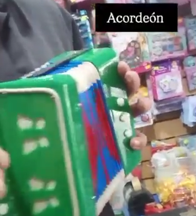 Primer plano de un acordeón verde con detalles rojos y azules en el pasillo de una tienda.