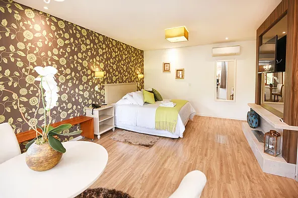 Um quarto com uma cama grande, mesa, cadeiras e televisão.