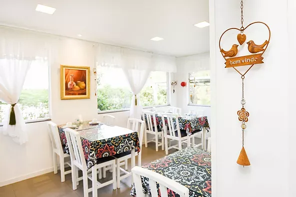 Uma sala de jantar com mesas e cadeiras e um coração pendurado na parede.