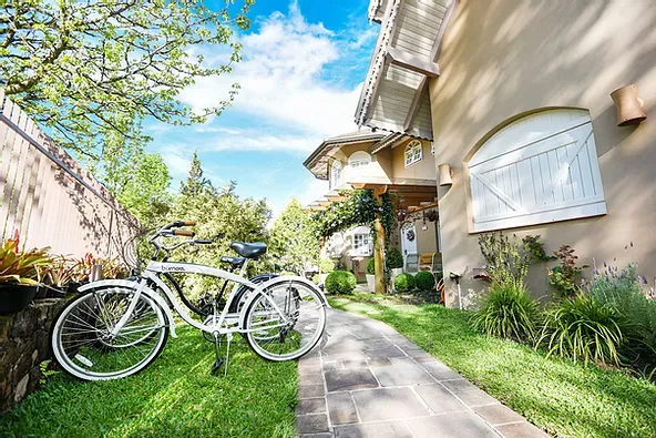 Duas bicicletas estão estacionadas na grama em frente a uma casa.