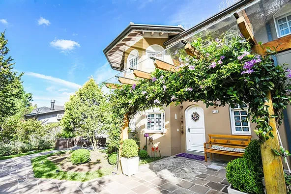 Uma casa grande com pergolado e um banco na frente.