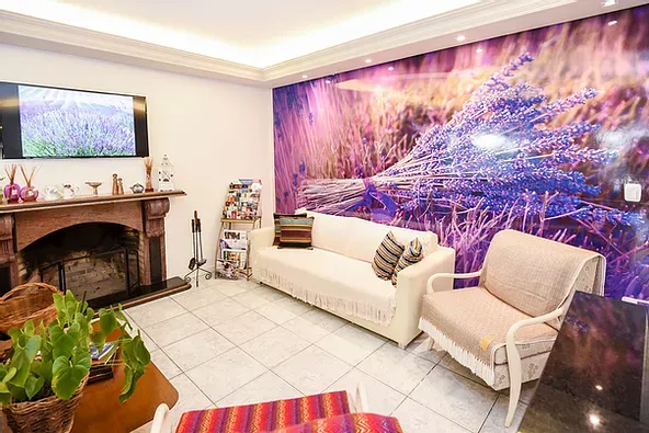 Uma sala de estar com sofá, cadeiras, lareira e um mural roxo.