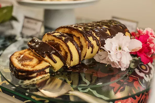 Uma fatia de bolo com cobertura de chocolate e flores em uma placa de vidro.