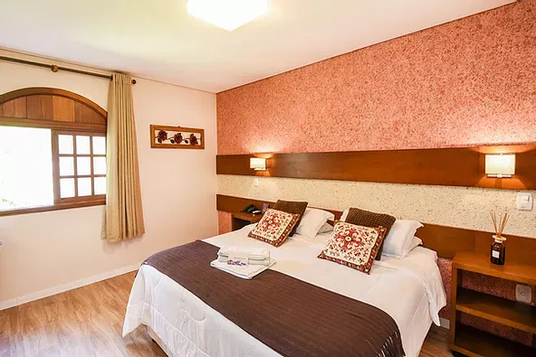 Um quarto de hotel com cama king size e janela.