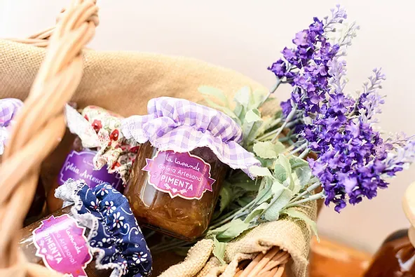 Uma cesta cheia de potes de geléia e flores roxas.