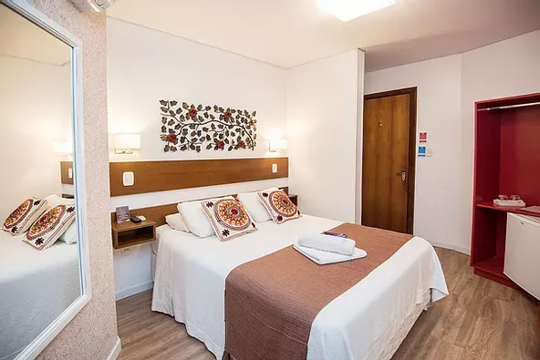Um quarto de hotel com uma cama grande e um espelho.