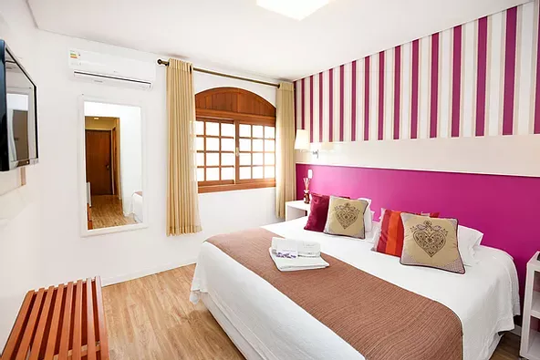 Um quarto de hotel com cama king size e parede listrada.
