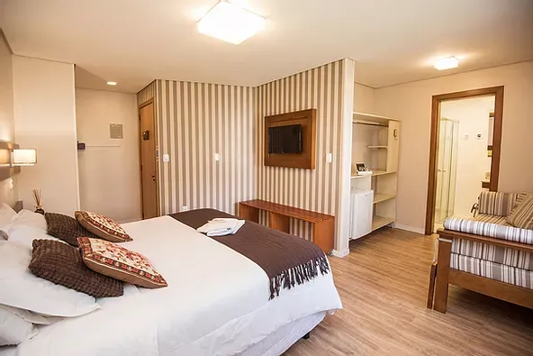 Um quarto de hotel com cama king size e TV de tela plana.