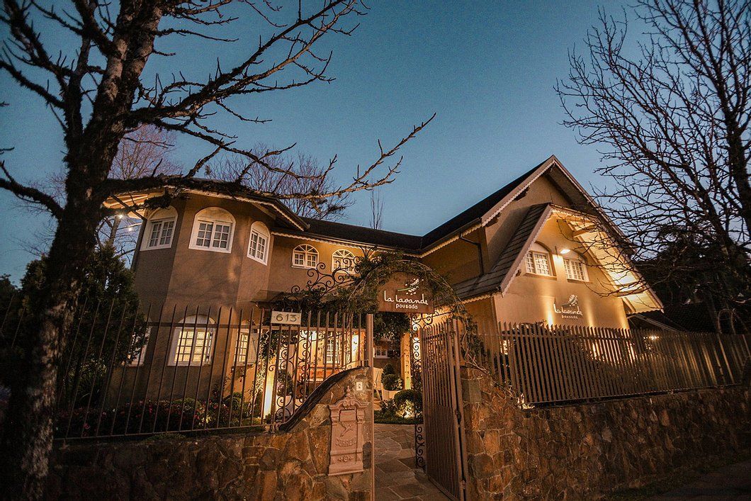 Uma grande casa com luzes de natal acesa é iluminada à noite.