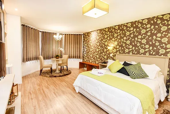 Um quarto de hotel com cama king size, mesa de jantar e cadeiras.