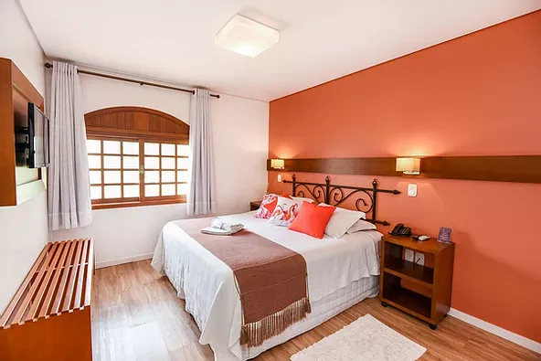 Um quarto de hotel com cama king size e janela.