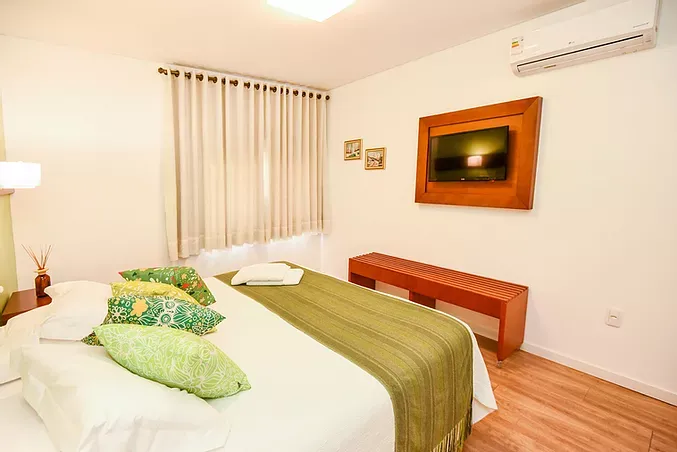 Um quarto com uma cama e uma televisão na parede.