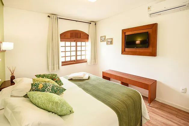 Um quarto com uma cama e uma televisão na parede.