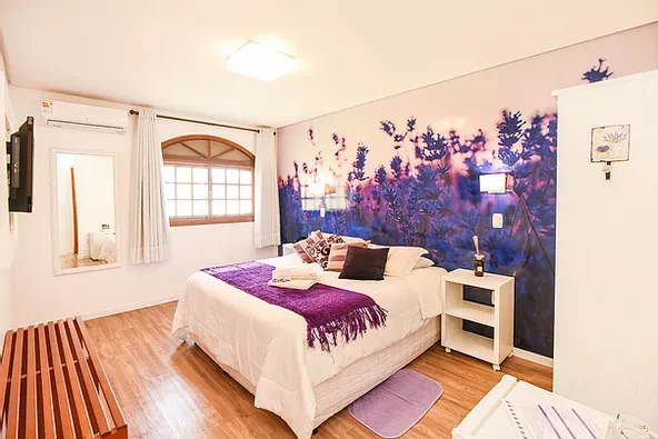 Um quarto com cama king size e cobertor roxo.
