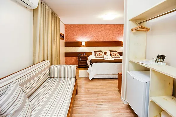 Um quarto de hotel com um sofá e uma cama.