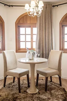 Há uma mesa e cadeiras na sala com um lustre.