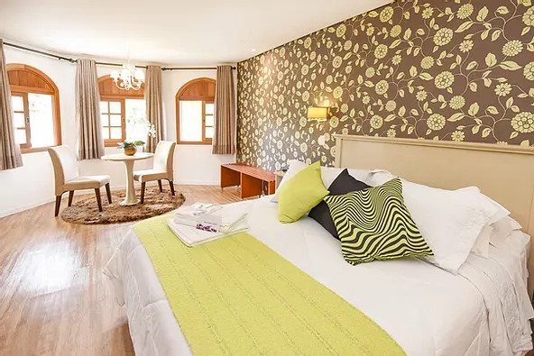 Um quarto de hotel com cama king size, mesa e cadeiras.