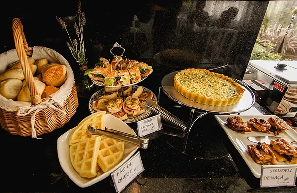Uma mesa de buffet com comida variada e uma cesta de pães.