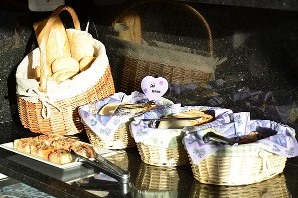 Uma cesta de pão fica sobre uma mesa ao lado de outras cestas