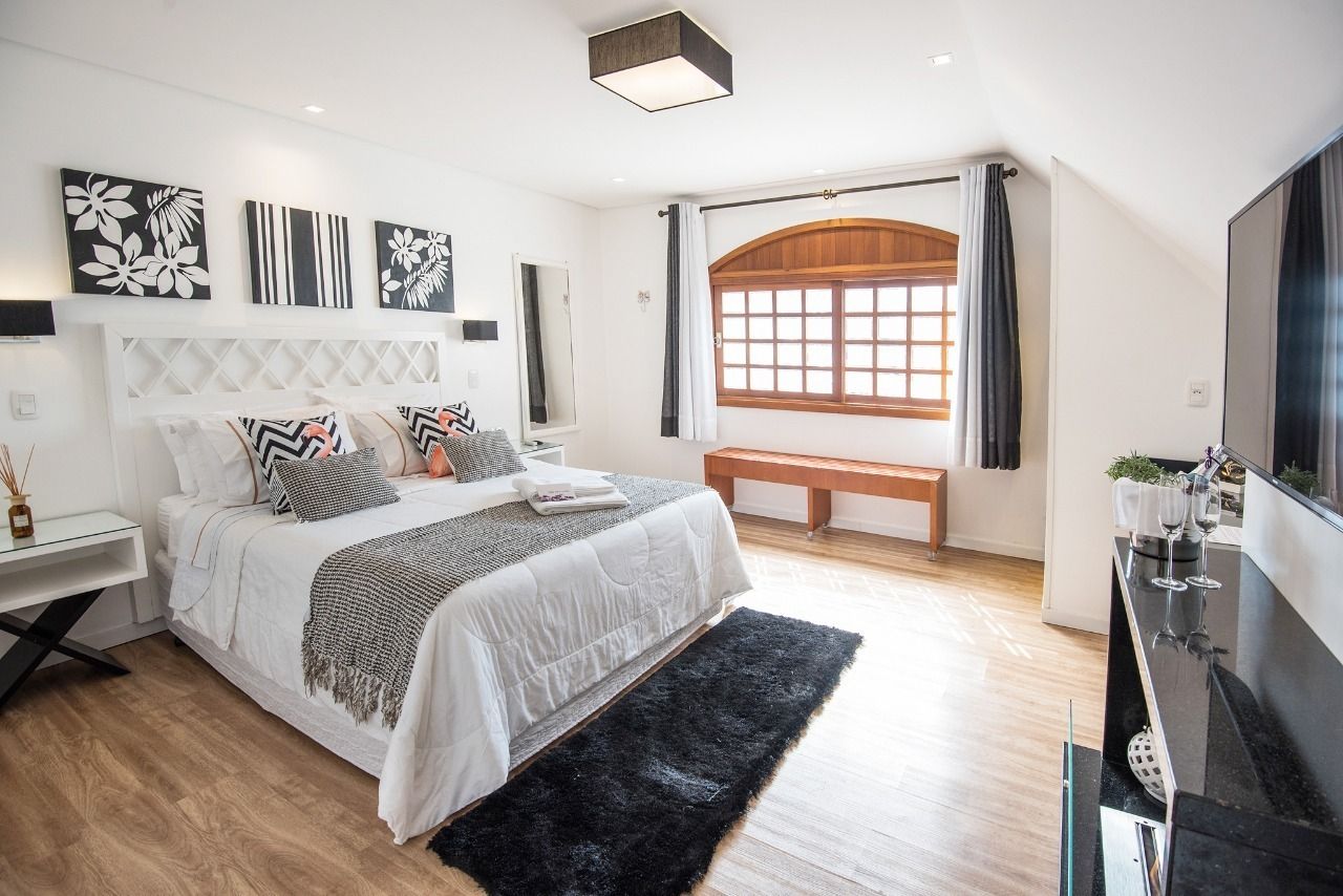Um quarto com cama king size, televisão e banco.
