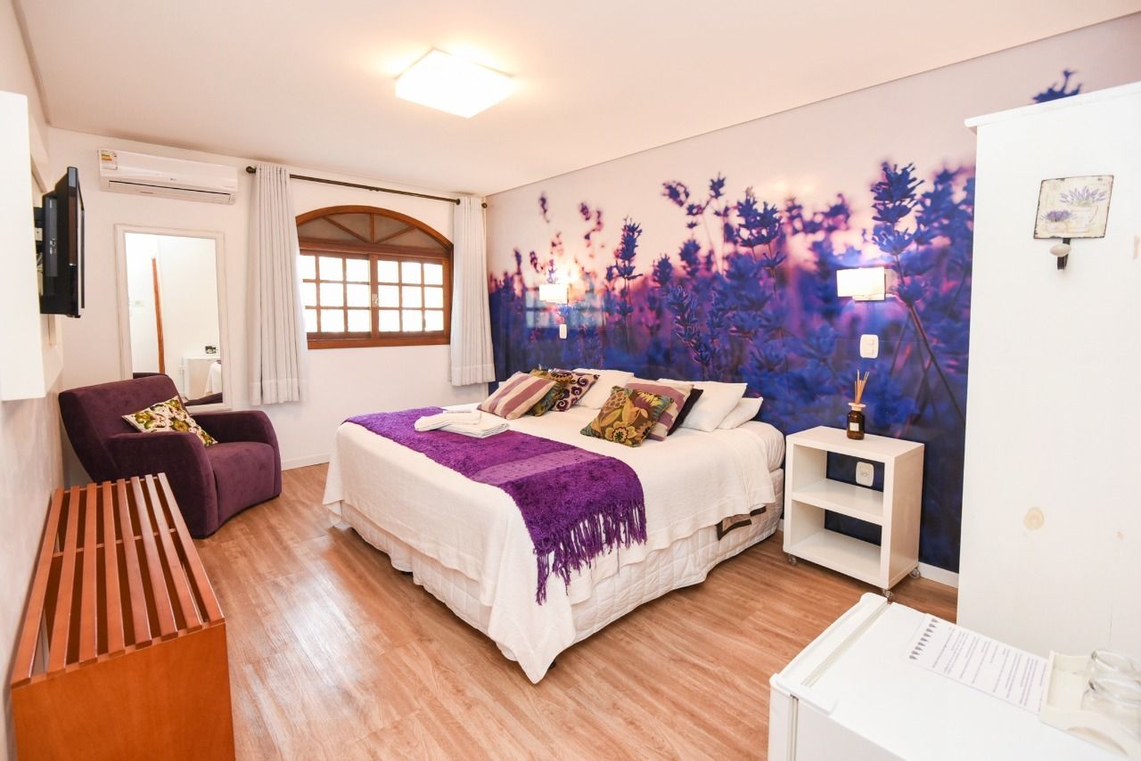 Um quarto de hotel com uma cama king size e uma cadeira roxa.