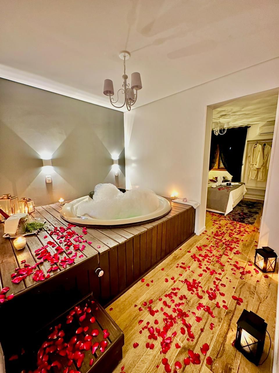 Um quarto com jacuzzi e pétalas de rosa no chão.
