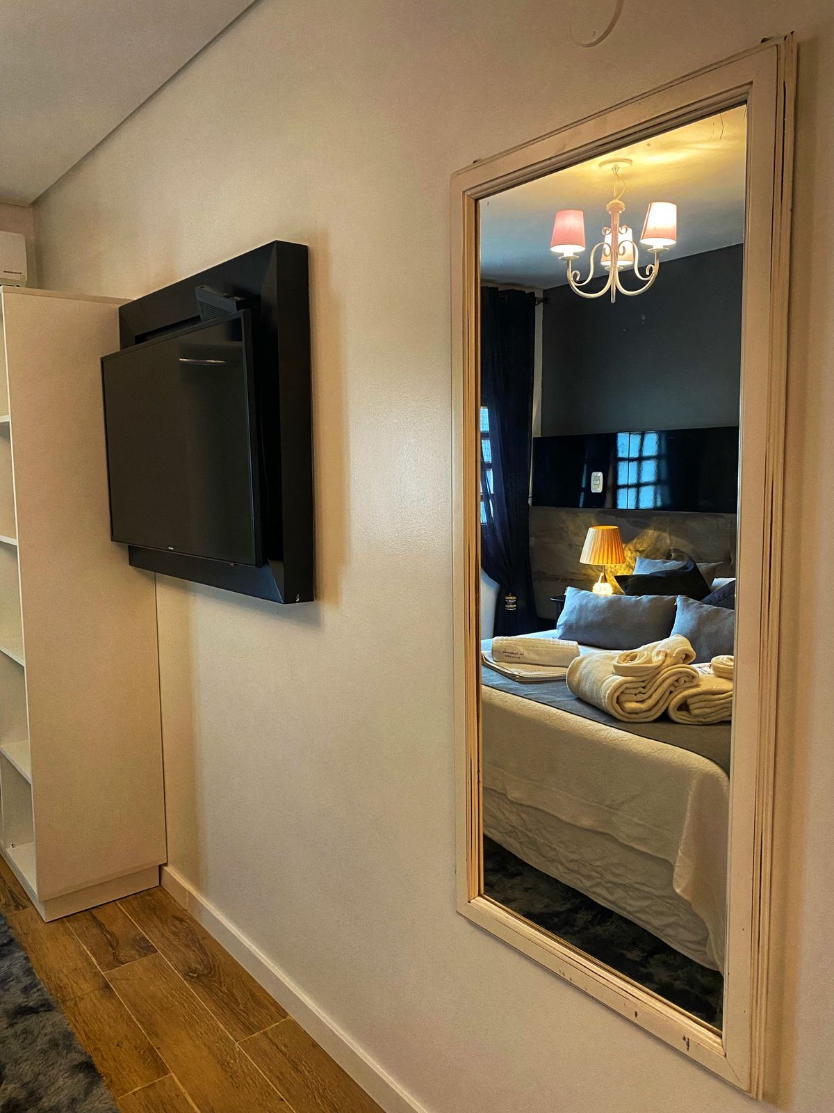 Um quarto com um espelho grande e uma TV de tela plana na parede.