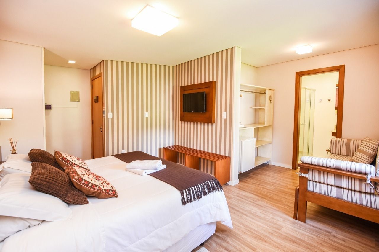 Um quarto de hotel com cama, sofá e televisão.