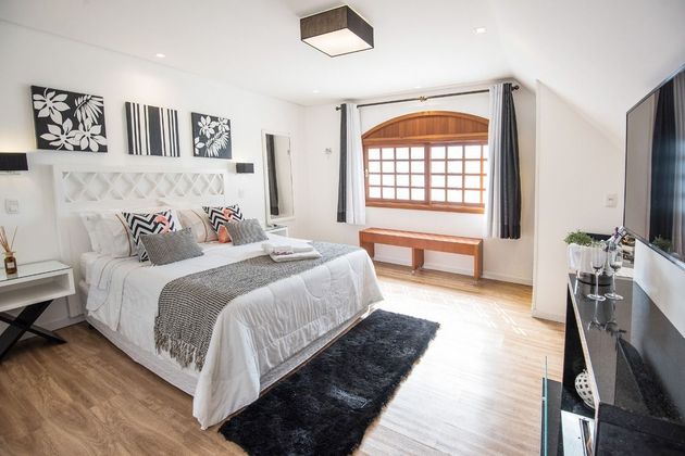 Um quarto com cama king size, televisão e banco.
