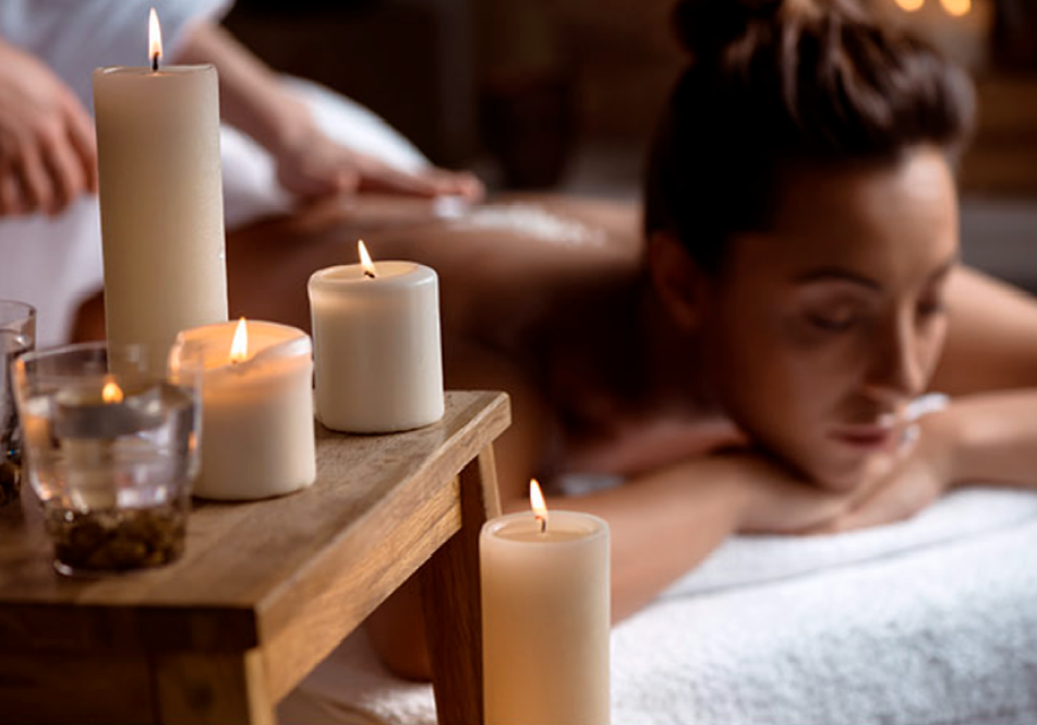 Uma mulher está recebendo uma massagem em um spa rodeado de velas.