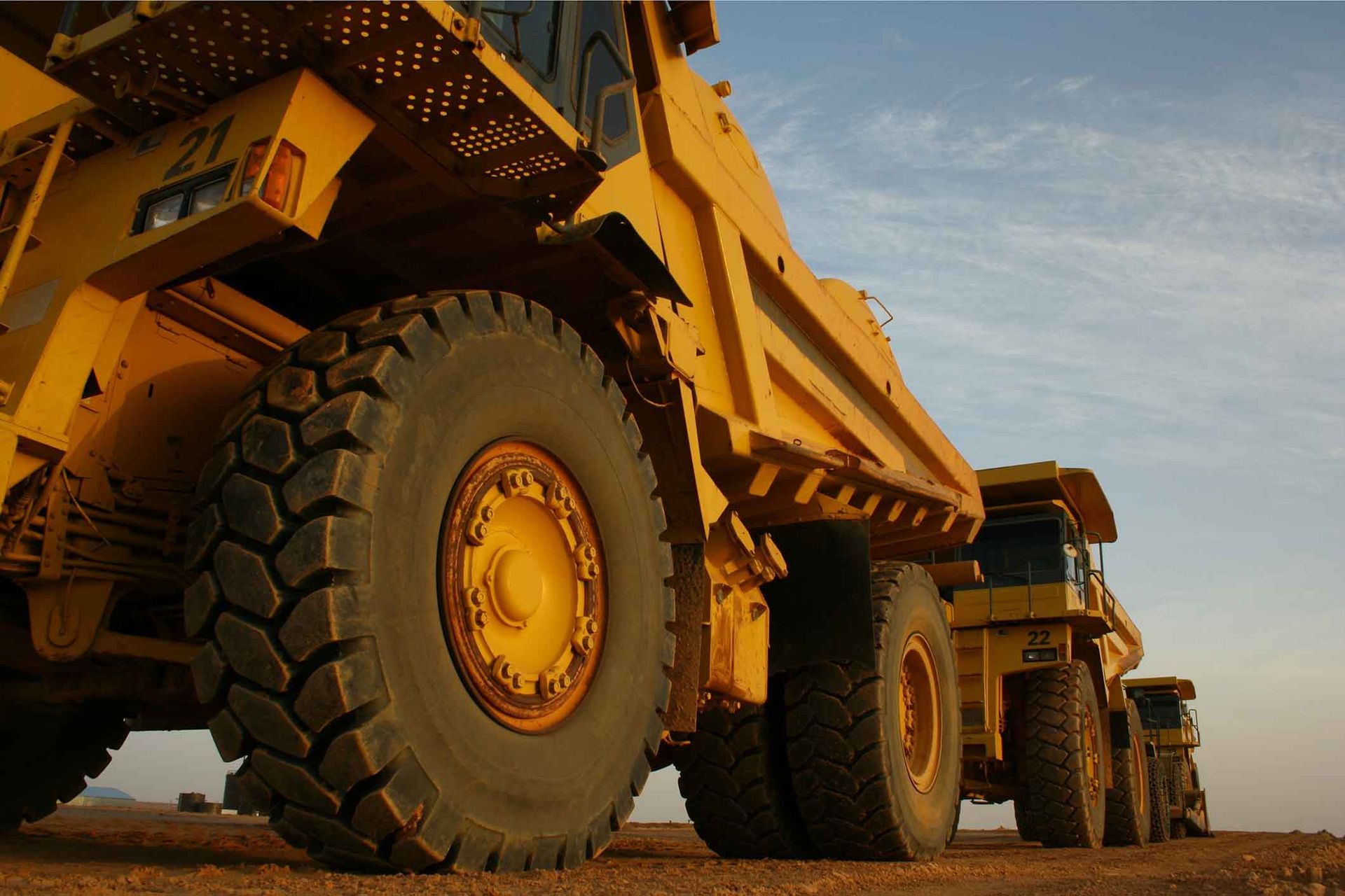 A Row Of Yellow Dump Trucks Are Parked In A Dirt Field – Delacombe, VIC - Transport Tyres