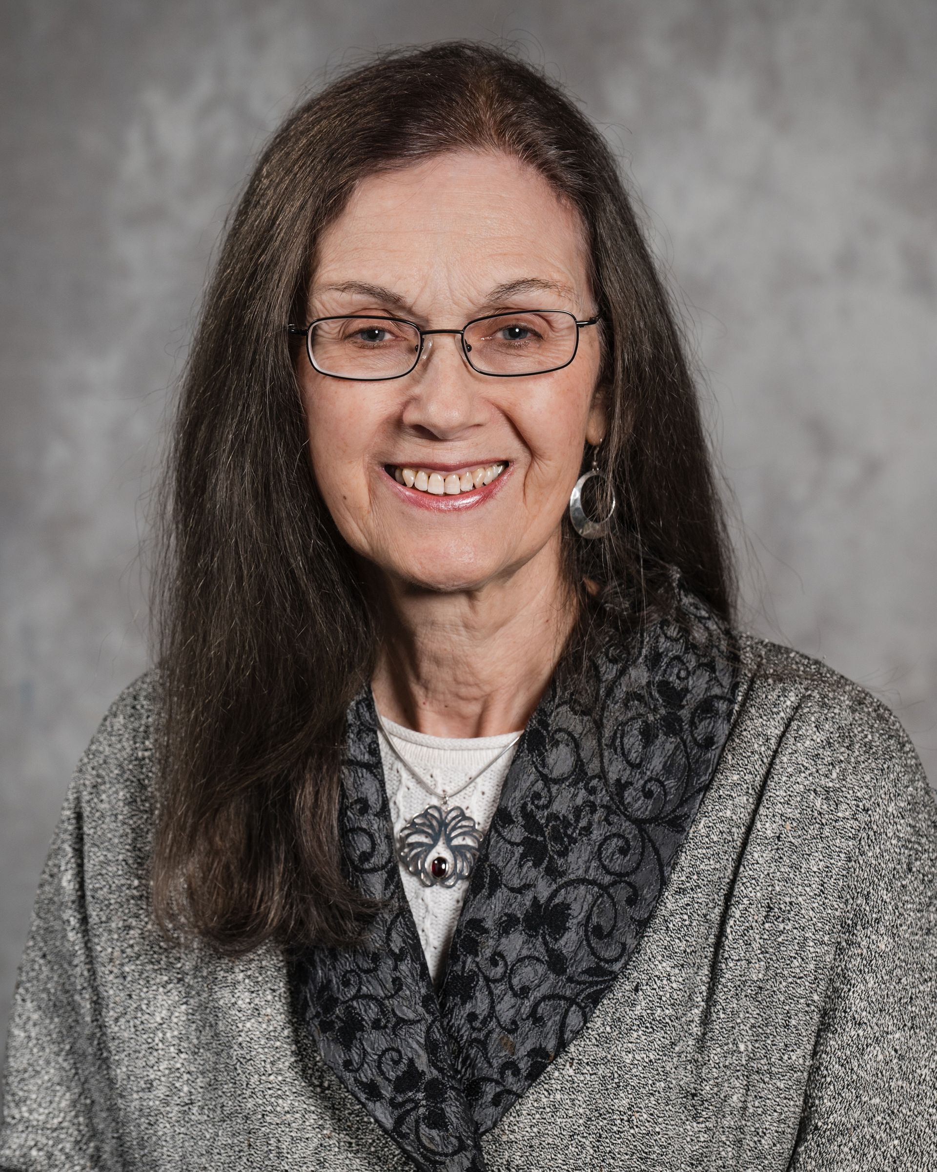 JUDITH P. LEAVITT, Ed.D Member, New England Recovery Associates | Serving Greater Boston A smiling person wearing glasses, a grey textured jacket, and a dark patterned scarf against a grey background.