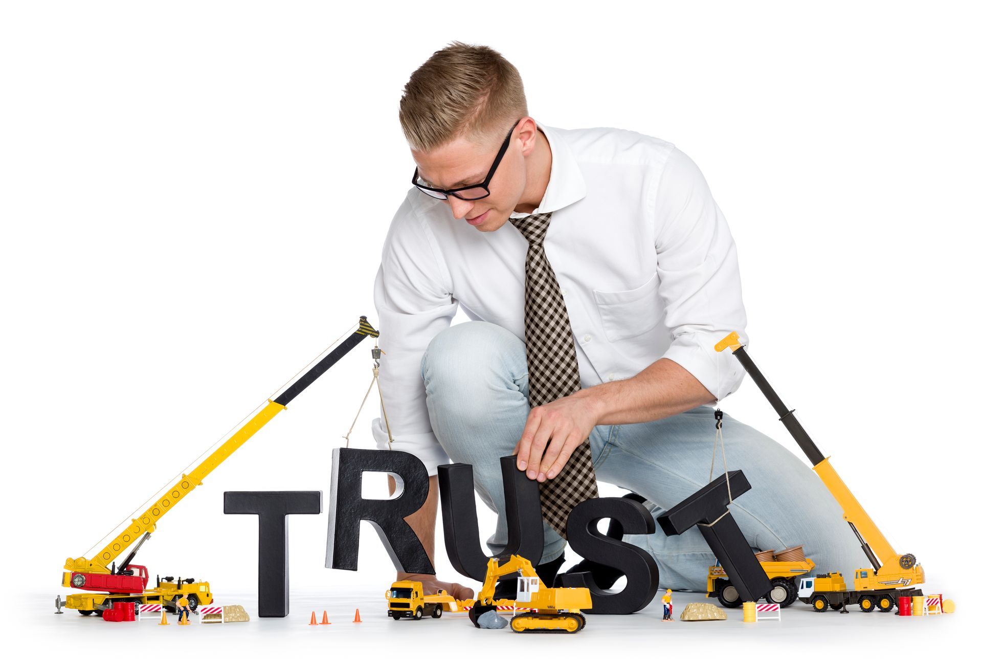 A person in a dress shirt and tie using toy construction vehicles to assemble the letters of the word TRUST.