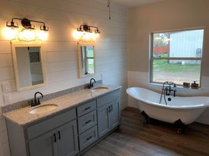 Bright bathroom with double vanity, wall mirrors, and a freestanding tub by a window