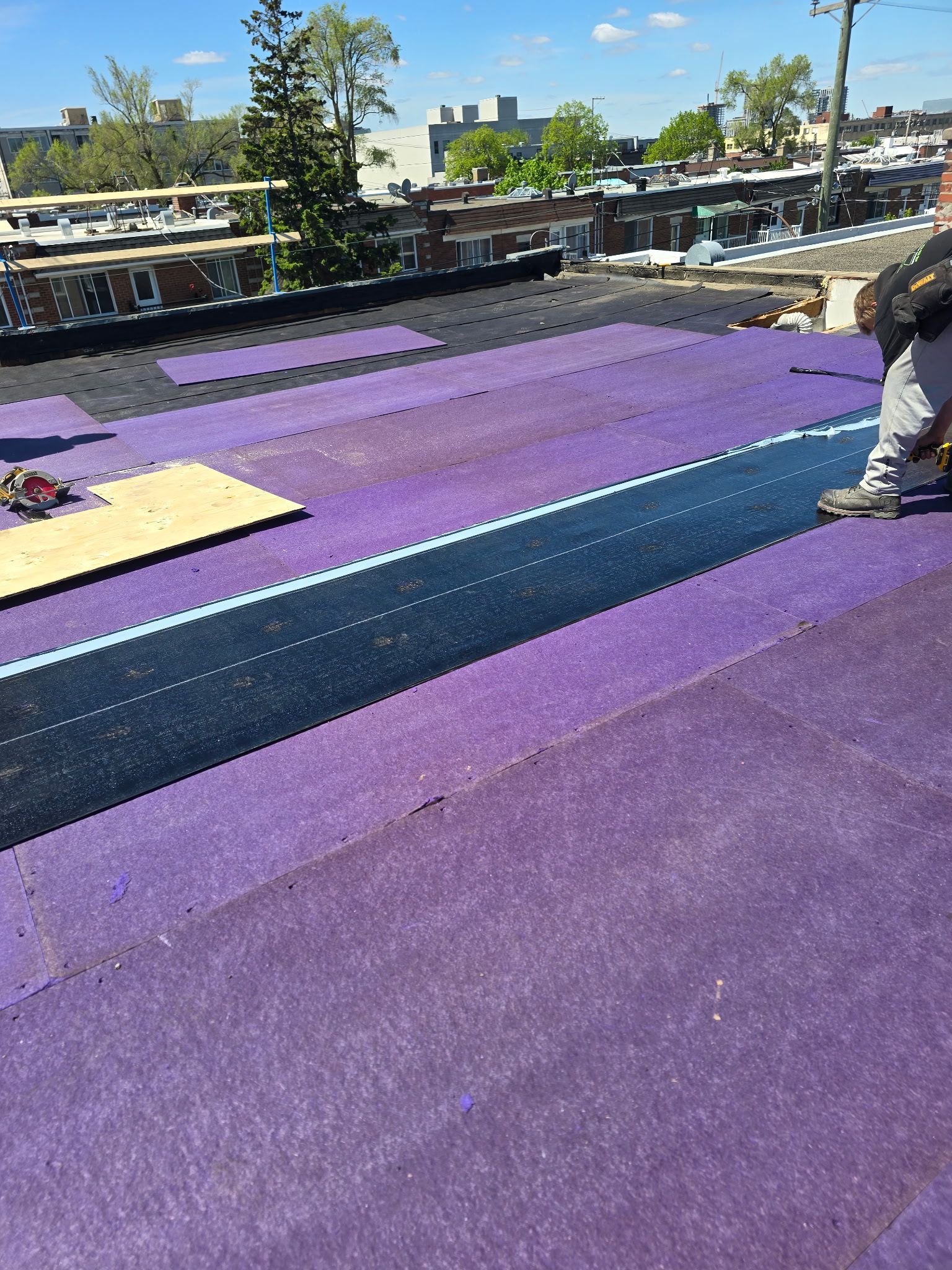Toit recouvert de moquette violette, un ouvrier se tenant au bord sous un ciel dégagé
