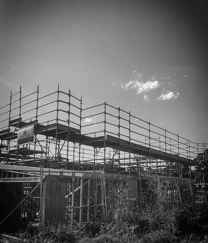 A Black and White Photo of a Building Under Construction With Scaffolding — RM Scaffolding Solutions in Ballina, NSW