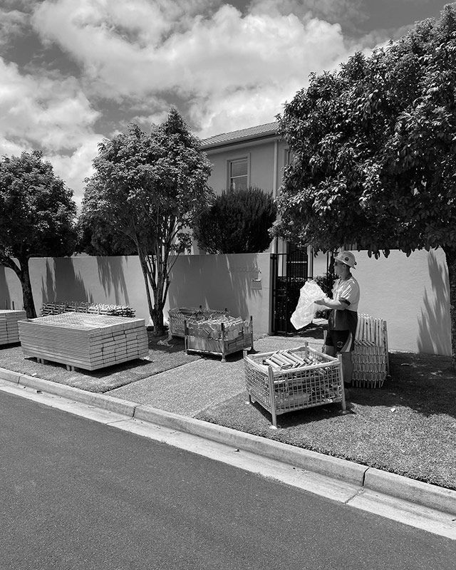 A Black and White Photo of a Man Sitting at a Table in Front of a House — RM Scaffolding Solutions in Northern Rivers, NSW