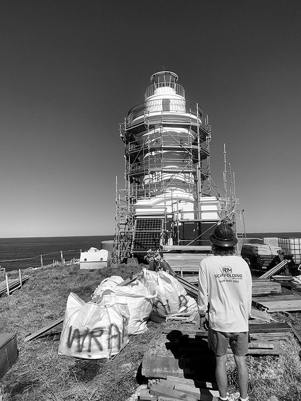 A Man is Standing in Front of a Lighthouse Under Construction — RM Scaffolding Solutions in Murwillumbah, NSW
