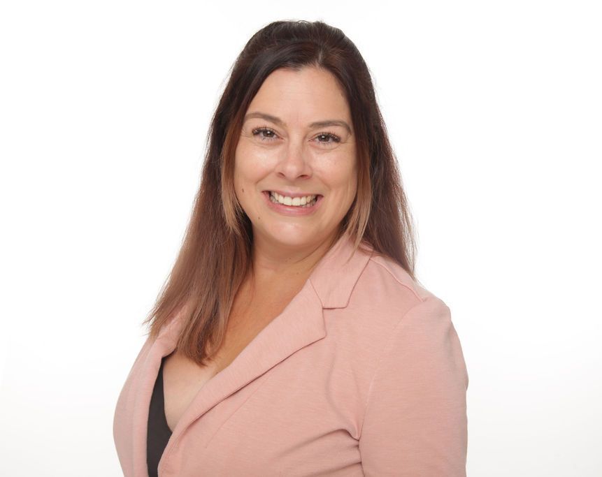 Smiling woman in a pink blazer against a white background