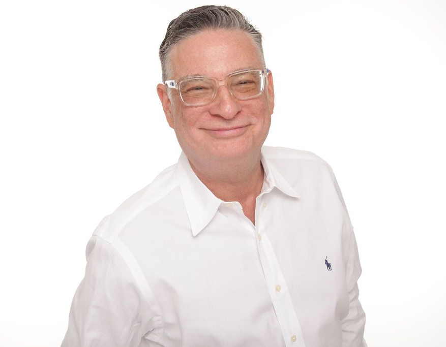 Smiling man in a white shirt and glasses against a plain white background