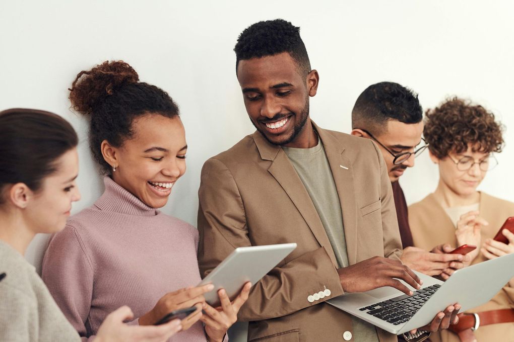 People collaborating with a tablet and laptop, smiling in a bright office setting