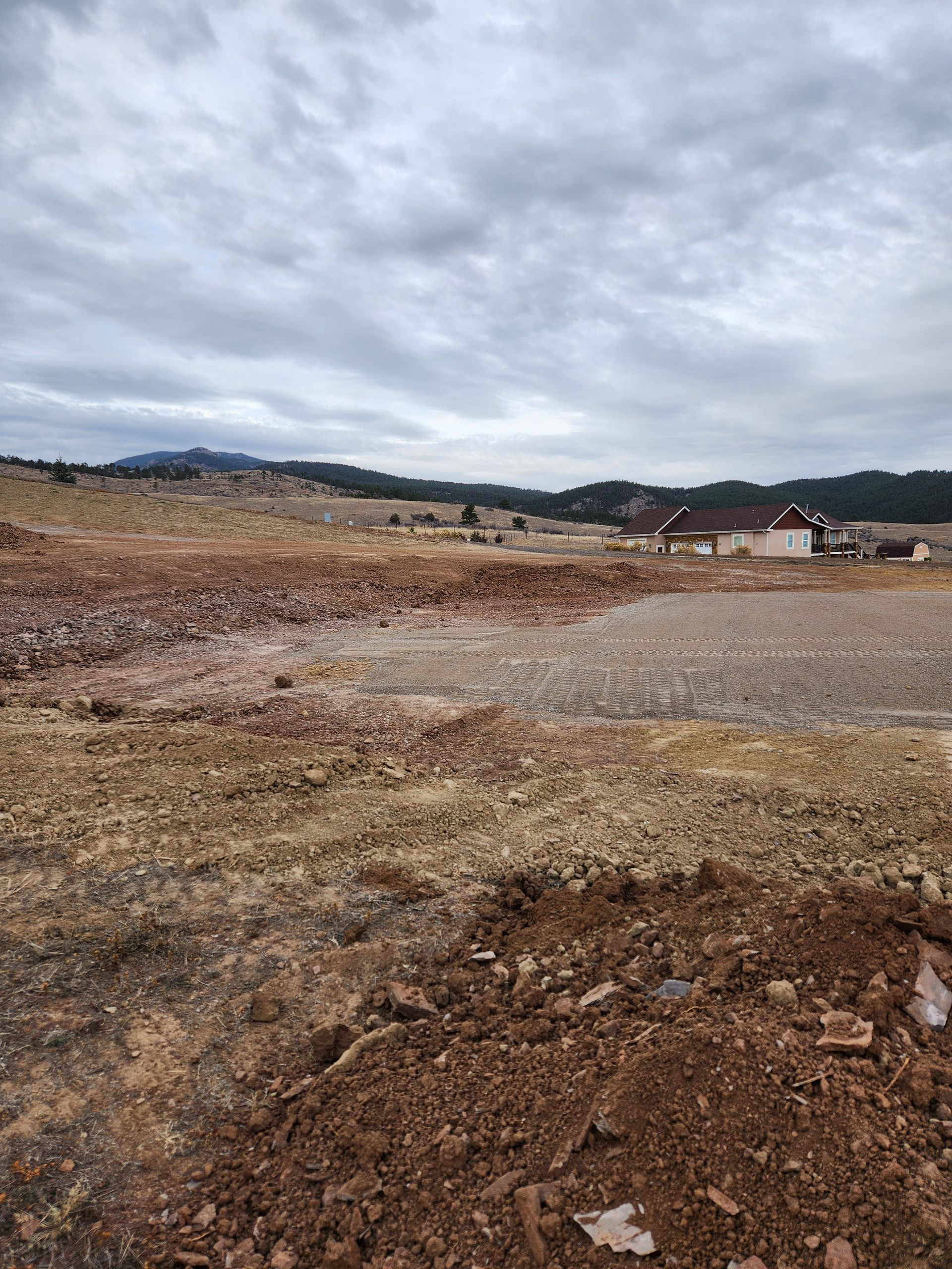 Cloudy rural landscape with bare, rocky ground and distant hills