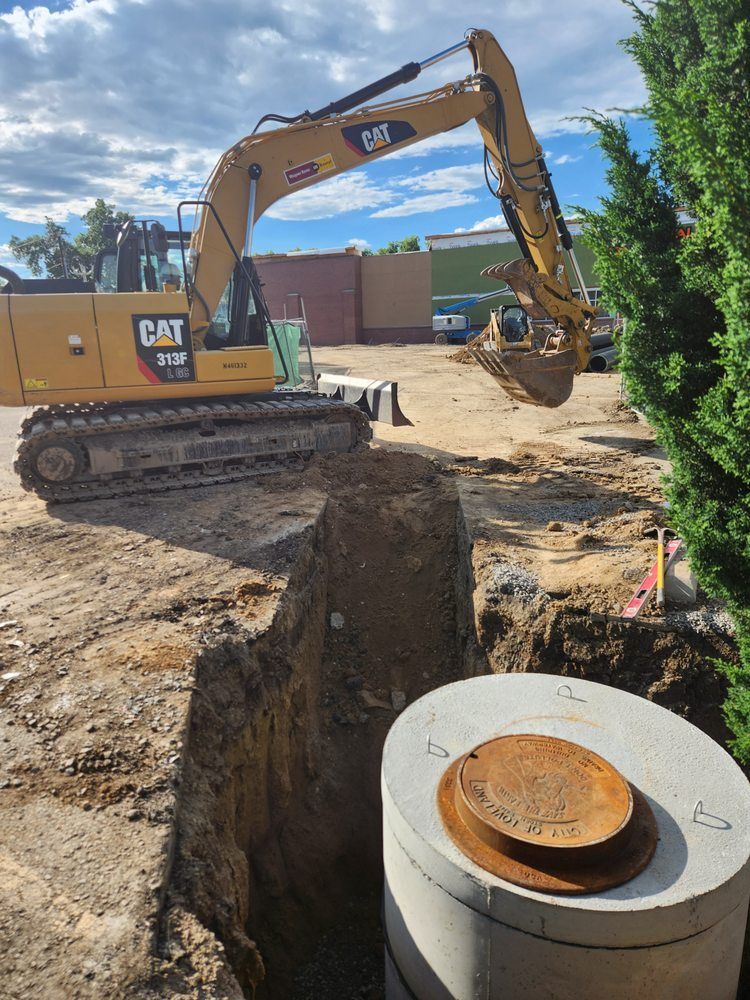 Yellow excavator digging near a concrete tank in a construction site.