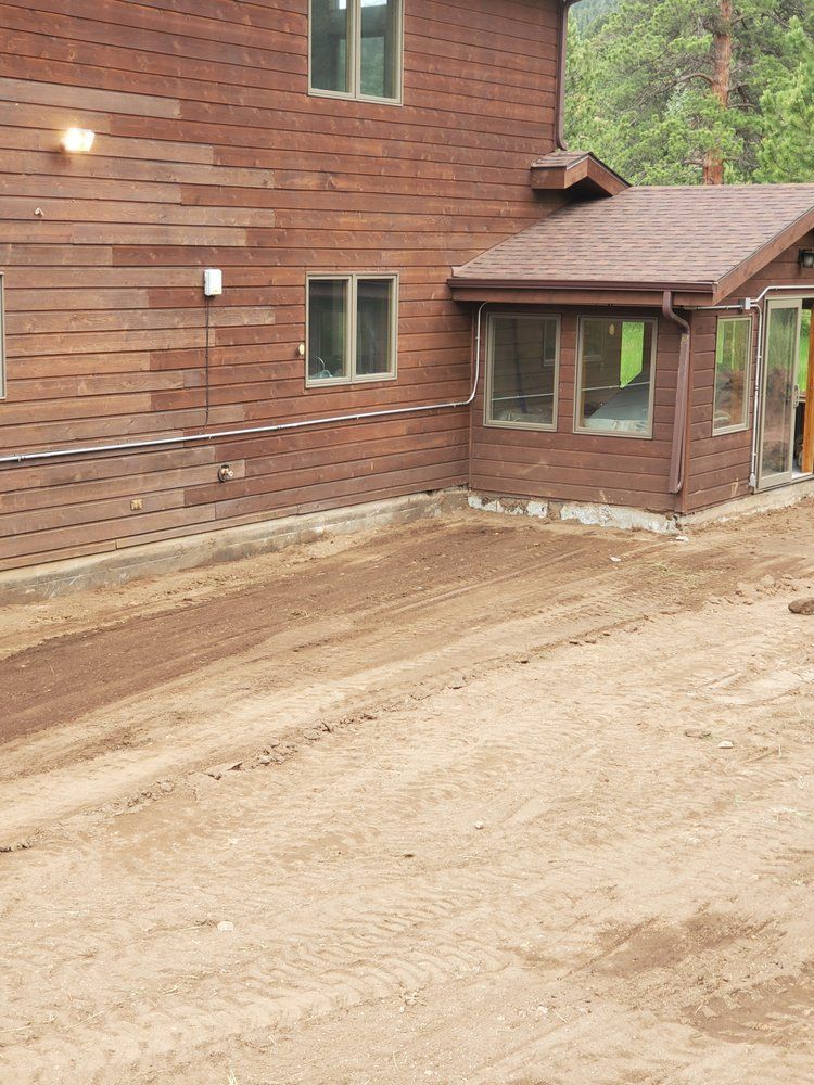 Brown house with dirt area in front; small porch with windows.