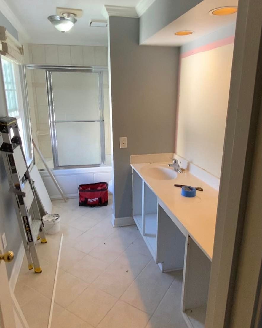 Bathroom renovation in progress; white sink counter, gray walls, shower stall.
